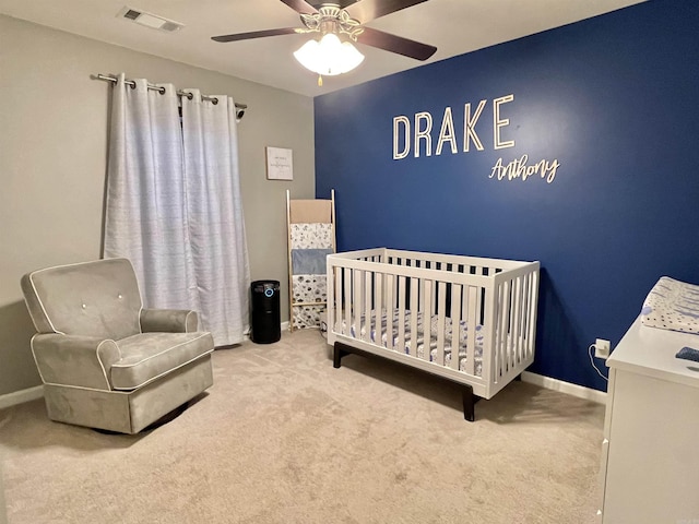 carpeted bedroom featuring visible vents, ceiling fan, a crib, and baseboards