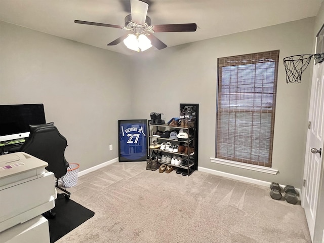 carpeted office space featuring baseboards and a ceiling fan