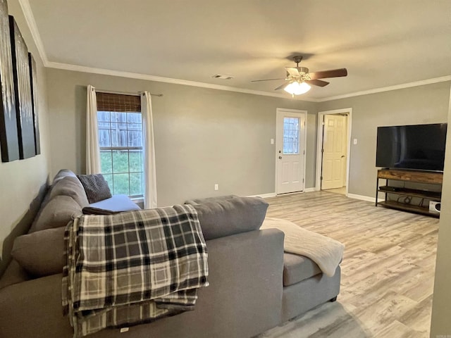 living room with a ceiling fan, crown molding, baseboards, and wood finished floors