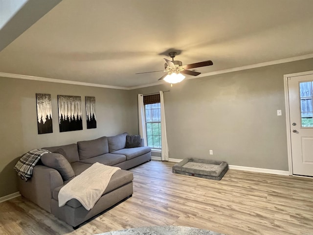 living area with crown molding, wood finished floors, a ceiling fan, and baseboards