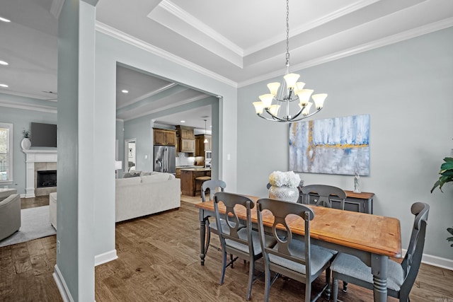 dining room featuring dark wood-type flooring, a tile fireplace, and crown molding