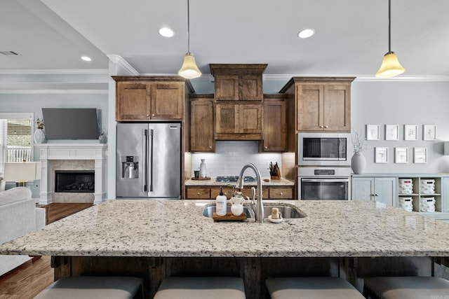 kitchen with a sink, appliances with stainless steel finishes, backsplash, a kitchen bar, and crown molding