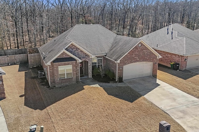 ranch-style home featuring an attached garage, driveway, fence, and brick siding