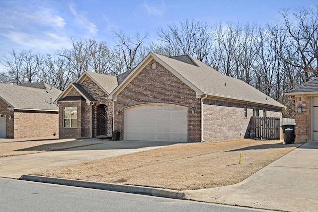 view of front facade with concrete driveway, brick siding, an attached garage, and a shingled roof