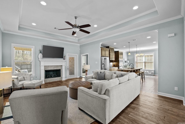 living room with dark wood-style floors, a raised ceiling, and plenty of natural light