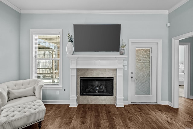 living area with baseboards, ornamental molding, wood finished floors, and a tile fireplace