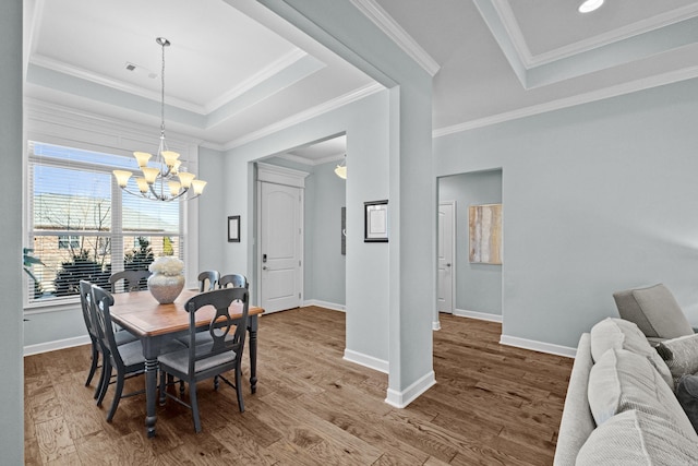 dining space featuring baseboards, visible vents, a tray ceiling, and wood finished floors