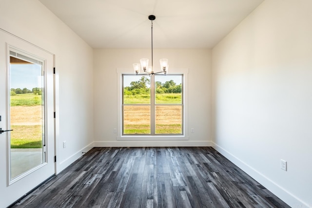 unfurnished dining area with plenty of natural light, a notable chandelier, baseboards, and dark wood-style flooring