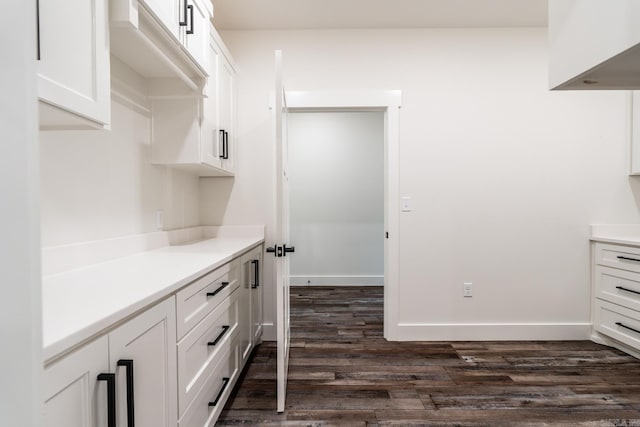 kitchen featuring baseboards, white cabinets, dark wood-type flooring, and light countertops