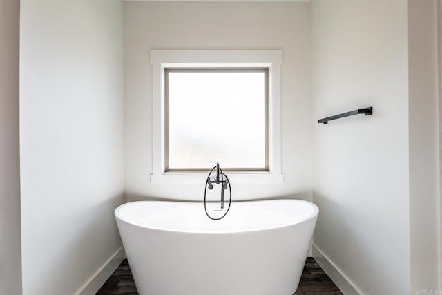 full bath featuring a freestanding tub, baseboards, and wood finished floors