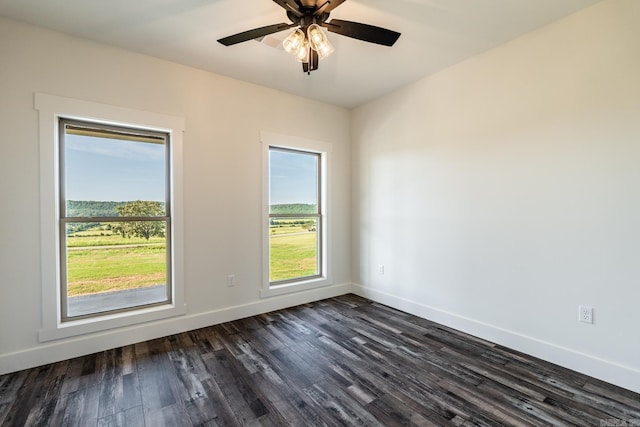 unfurnished room featuring ceiling fan, dark wood finished floors, and baseboards