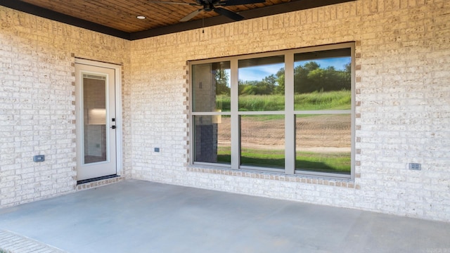 view of exterior entry featuring a patio area, brick siding, and ceiling fan