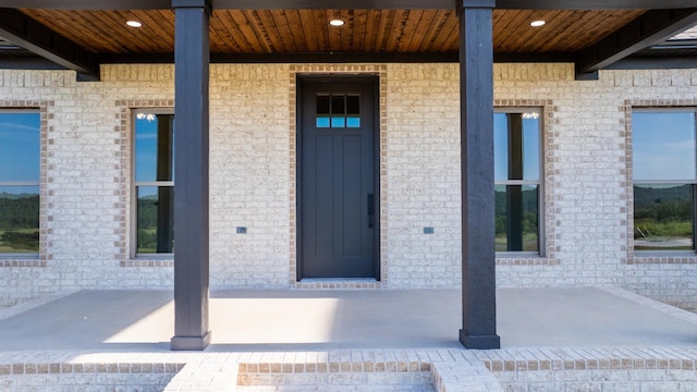 property entrance with a porch and brick siding