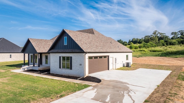 view of side of property with brick siding, a yard, board and batten siding, central AC, and a garage