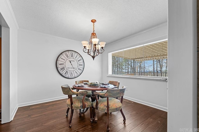 dining area with a textured ceiling, ornamental molding, dark wood-style flooring, and a notable chandelier