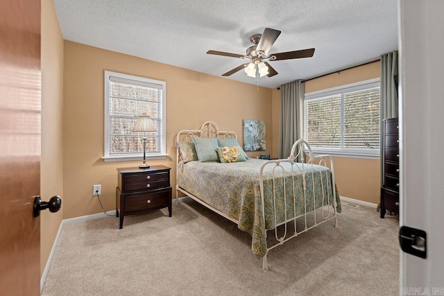 carpeted bedroom featuring a ceiling fan, a textured ceiling, and baseboards