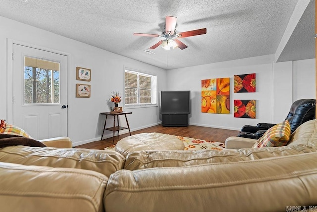 living room featuring ceiling fan, a textured ceiling, visible vents, and wood finished floors