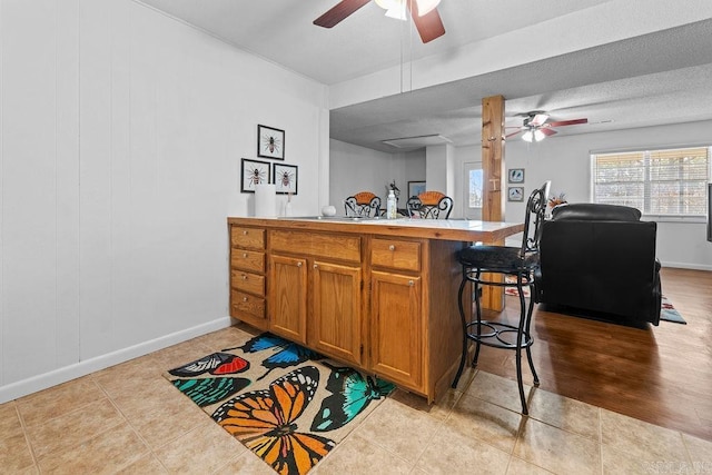 kitchen with brown cabinets, light countertops, open floor plan, a peninsula, and a kitchen breakfast bar