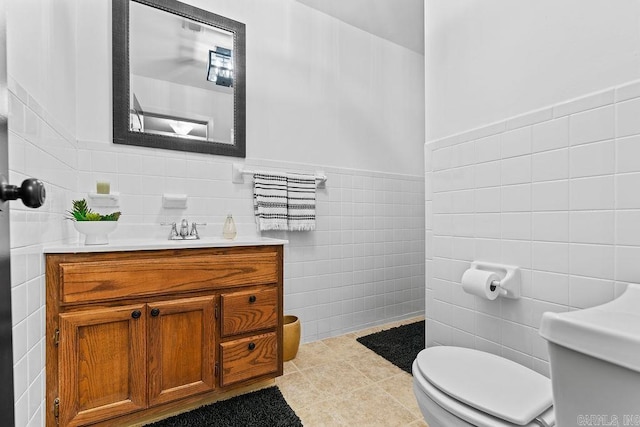 bathroom with toilet, tile patterned floors, tile walls, and vanity