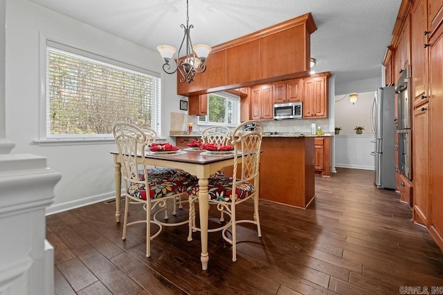 dining area featuring an inviting chandelier, a textured ceiling, baseboards, and dark wood-type flooring