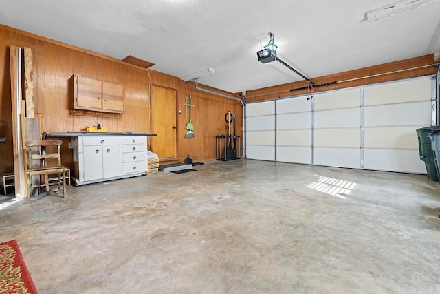 garage with a garage door opener and wood walls