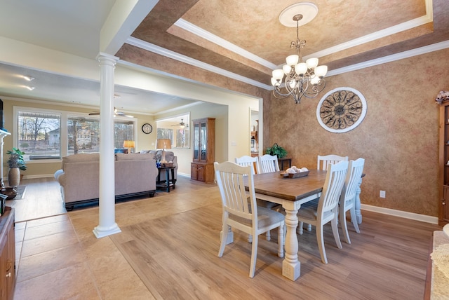 dining space with light wood finished floors, a tray ceiling, decorative columns, and baseboards