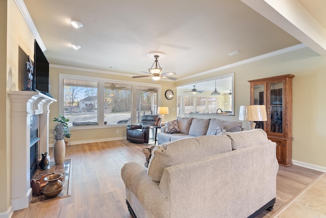 living room with light wood finished floors, a fireplace with flush hearth, baseboards, and crown molding