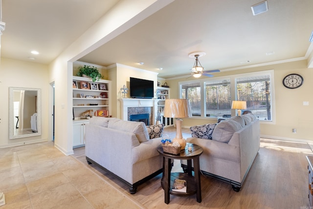 living area featuring crown molding, visible vents, a fireplace, and baseboards