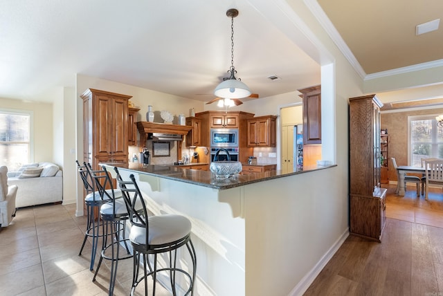 kitchen with brown cabinets, a breakfast bar, stainless steel appliances, and decorative backsplash