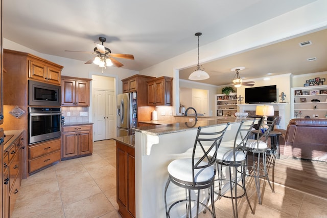 kitchen with open floor plan, stainless steel appliances, a breakfast bar, and brown cabinetry