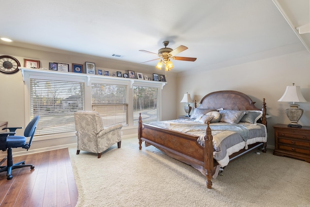 bedroom with a ceiling fan, wood finished floors, visible vents, and multiple windows