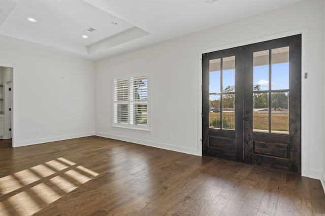 foyer entrance with a wealth of natural light, french doors, a raised ceiling, and hardwood / wood-style floors