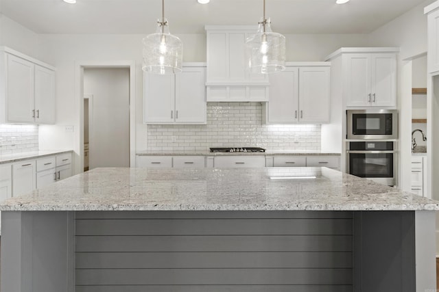 kitchen with stainless steel appliances, tasteful backsplash, a kitchen island, and white cabinetry