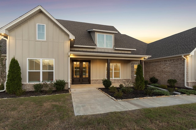 view of front of house with french doors, brick siding, roof with shingles, and board and batten siding