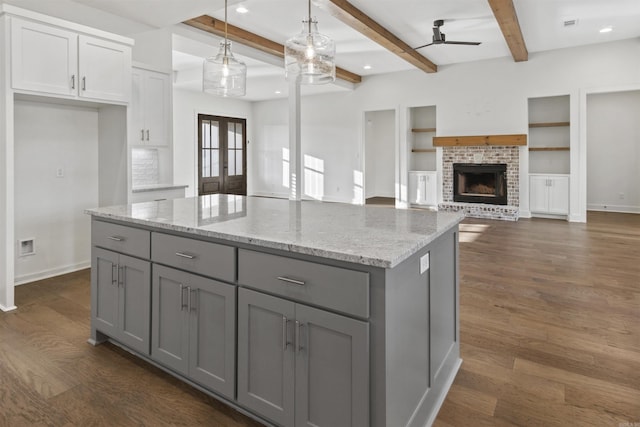 kitchen featuring gray cabinetry, dark wood-style flooring, a kitchen island, french doors, and a brick fireplace