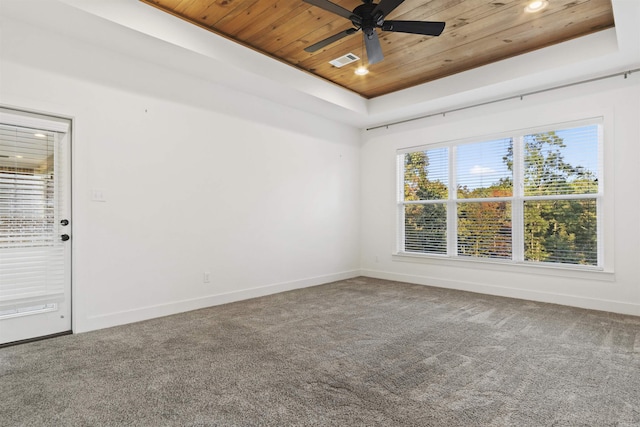 spare room featuring carpet floors, a tray ceiling, visible vents, wooden ceiling, and baseboards