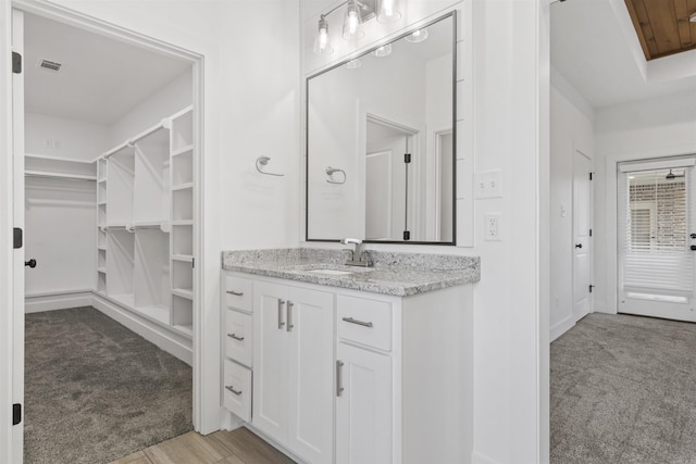 bathroom featuring a spacious closet, visible vents, and vanity