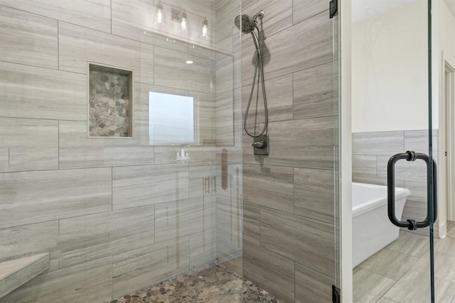 bathroom featuring a freestanding bath, tile walls, and tiled shower