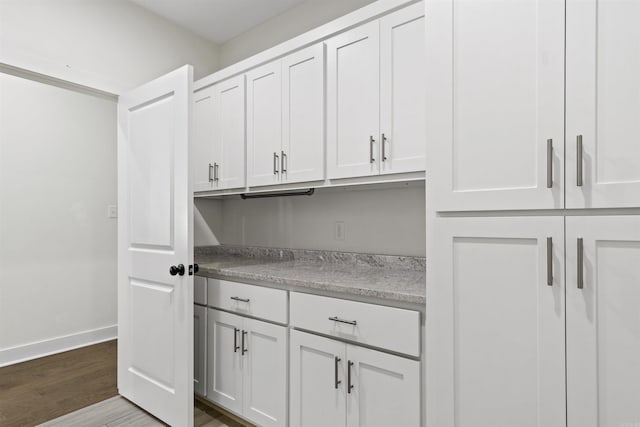 interior space with dark wood-style floors, baseboards, white cabinetry, and light countertops