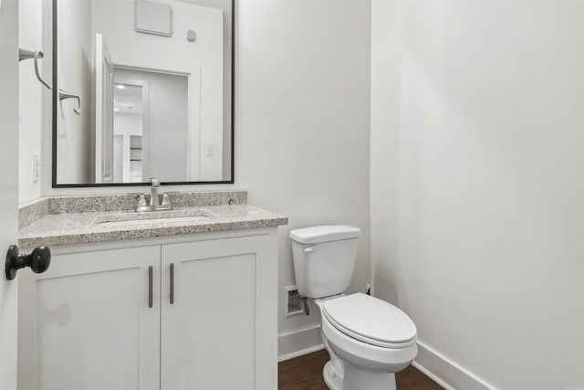 bathroom featuring baseboards, vanity, toilet, and wood finished floors