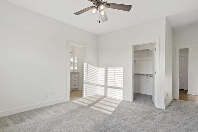 unfurnished bedroom with carpet, a spacious closet, baseboards, and a closet