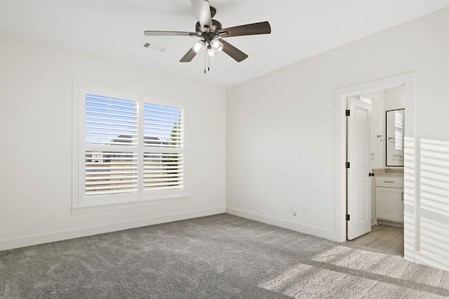 unfurnished bedroom featuring light carpet, ceiling fan, baseboards, and connected bathroom