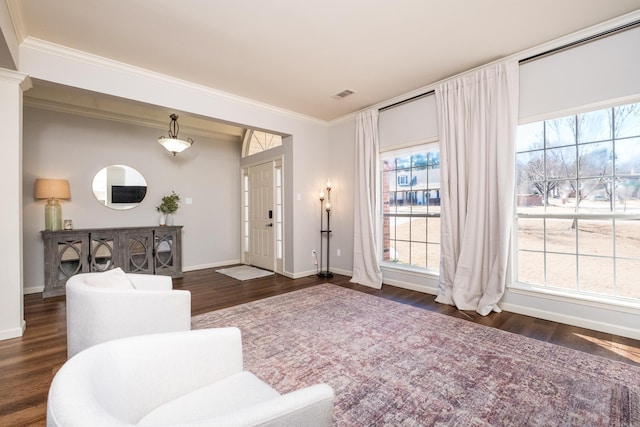 living area with baseboards, dark wood finished floors, visible vents, and crown molding