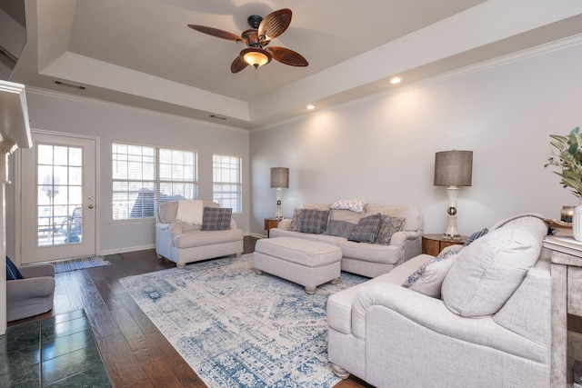 living room featuring crown molding, visible vents, a raised ceiling, and dark wood-style flooring