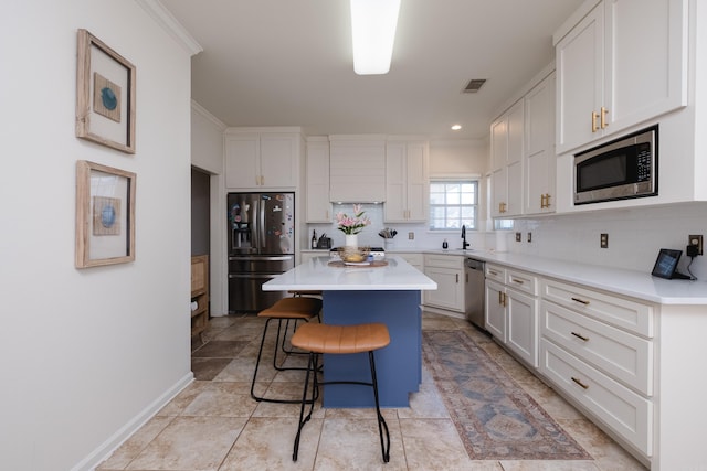 kitchen featuring visible vents, a kitchen island, appliances with stainless steel finishes, a breakfast bar, and light countertops