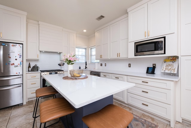 kitchen with tasteful backsplash, light countertops, visible vents, appliances with stainless steel finishes, and white cabinetry