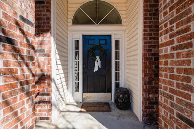 view of exterior entry featuring brick siding