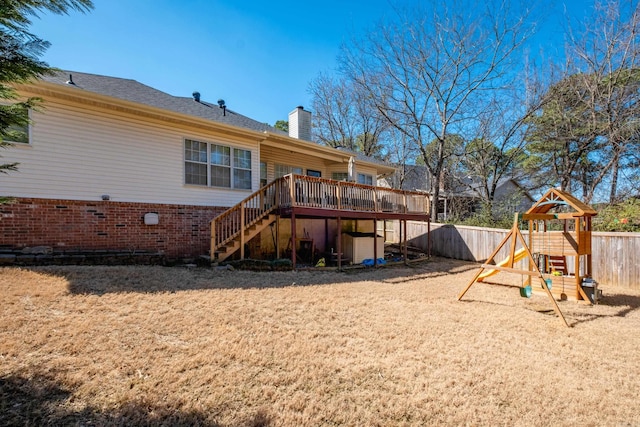 rear view of property featuring a playground, fence, stairway, a wooden deck, and a chimney