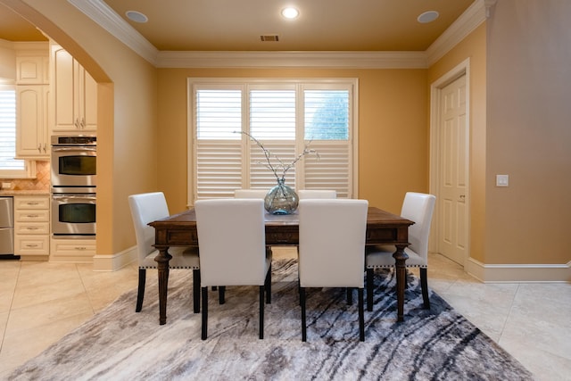 dining room featuring arched walkways, light tile patterned flooring, crown molding, and baseboards