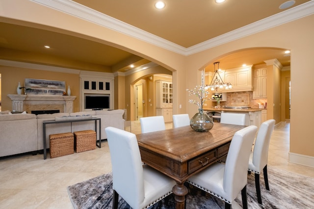 dining room with arched walkways, a fireplace, crown molding, recessed lighting, and baseboards